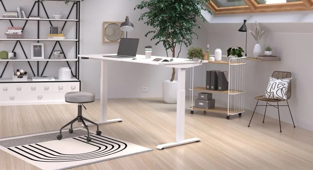 Helles Büro im Dachgeschoss mit einem höhenverstellbaren Schreibtisch in Weiß, davor ein kleiner runder Hocker mit Rollen. Im Hintergrund Regale und Container mit Akten.