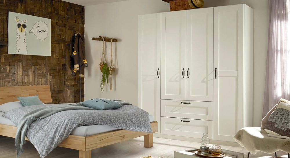 Ein gemütliches Schlafzimmer mit einem Bett mit weicher Bettwäsche und Kissen, einem eleganten weißen Schrank, Hartholzböden und einer Fensterdekoration.